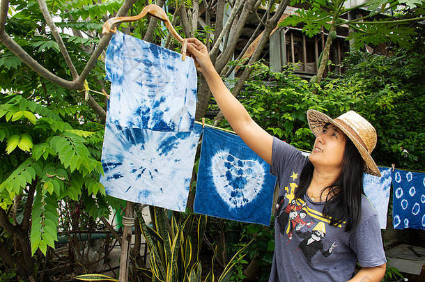 泰国妇女扎染蜡染手帕扎染蜡染靛蓝色或毛姆色，并在阳光下晾晒在花园室外的衣服