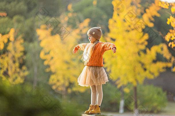 可爱时尚的小女孩漫步在银杏树环绕的秋天公园。秋季儿童时尚。快乐的童年。生活写真
