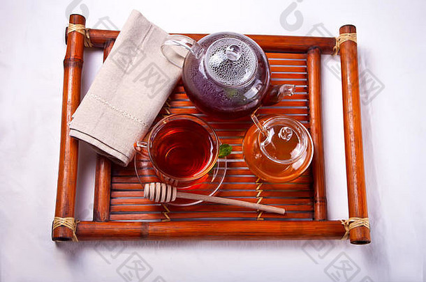 一杯热茶，茶壶和蜂蜜放在木制托盘上