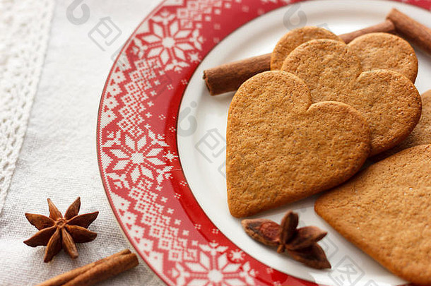 姜饼心形饼干，红盘上有肉桂棒和八角星