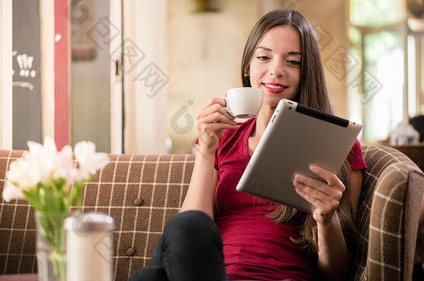 当代年轻的女人阅读平板电脑咖啡商店