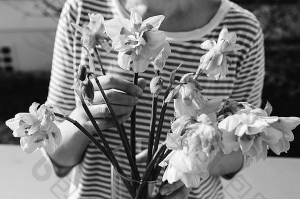 放松的女人摆好姿势，带着死水仙花束的花瓶的前视图-黑白图像