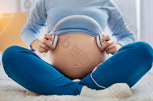 孕妇手持耳机的特写镜头