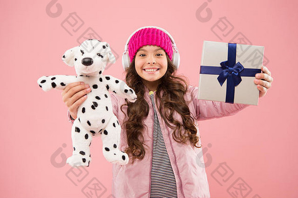 送给少女的最好礼物。时尚的女学生玩狗玩具，拿着礼品盒。小女孩戴着耳机，带着柔软的玩具。带上你最喜欢的玩具。快乐童年的概念。