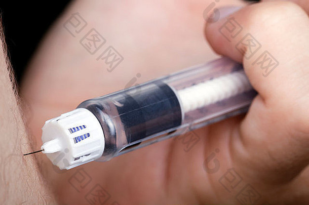 一只手拿着一个装满胰岛素的注射器，准备刺穿一名患有糖尿病的年轻成年男子的手臂。