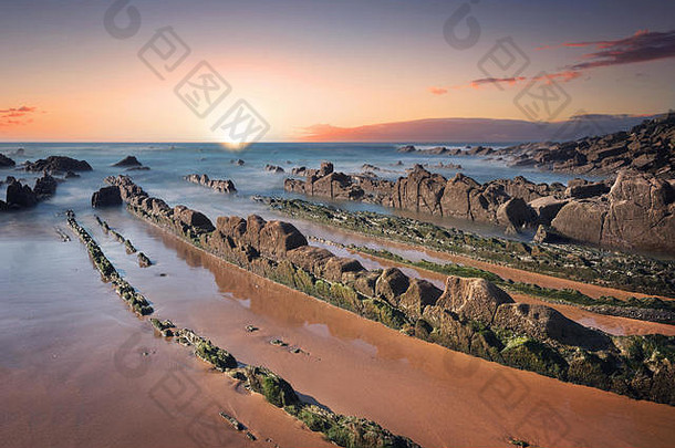 巴里卡海滩风景如画的日落，长满青苔的岩石。毕尔巴鄂，巴斯克国家，西班牙。
