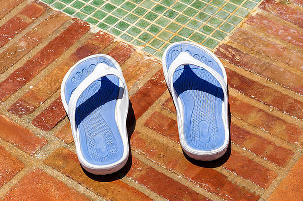 泳池淋浴旁边的人字拖拖鞋的特写镜头是蓝色和白色的。在假日。