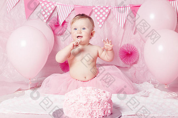 可爱可爱的白人的肖像，蓝色眼睛，穿着粉色短裙，用美味的蛋糕和气球庆祝她的一岁生日