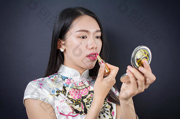 美丽的年轻的亚洲女人应用化妆脸