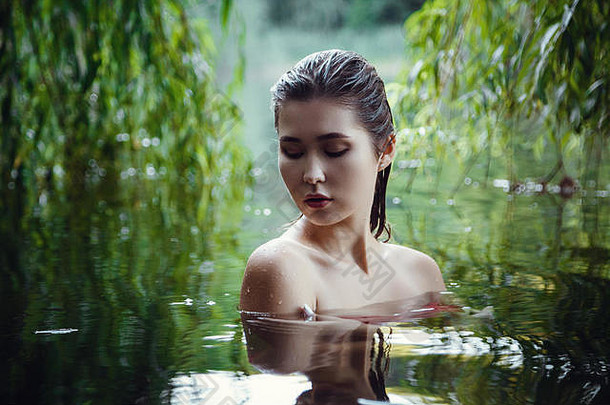 美丽的小女孩在水中休息。女人盲目地漂浮在河里，在水中沉思