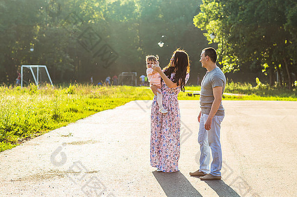 快乐的年轻一家人在公园里散步。