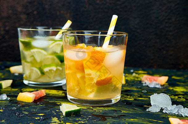 健康的排毒柑橘水或柠檬水在黑暗的背景。夏日柠檬、酸橙、橙子和葡萄柚鸡尾酒，令人耳目一新