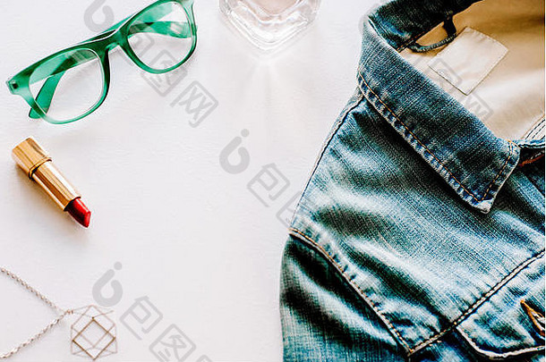 蓝色牛仔裤夹克、项链、香水和绿色眼镜俯视图。平放照片。