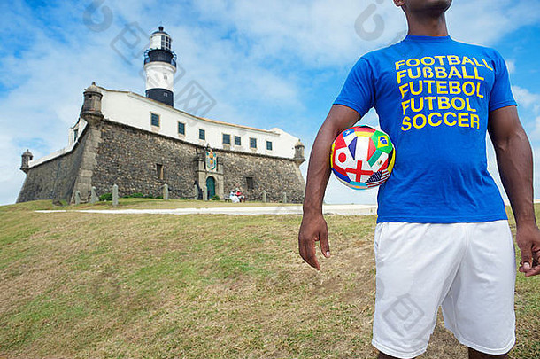 巴西足球运动员与国际足球队一起站在巴西萨尔瓦多的灯塔前