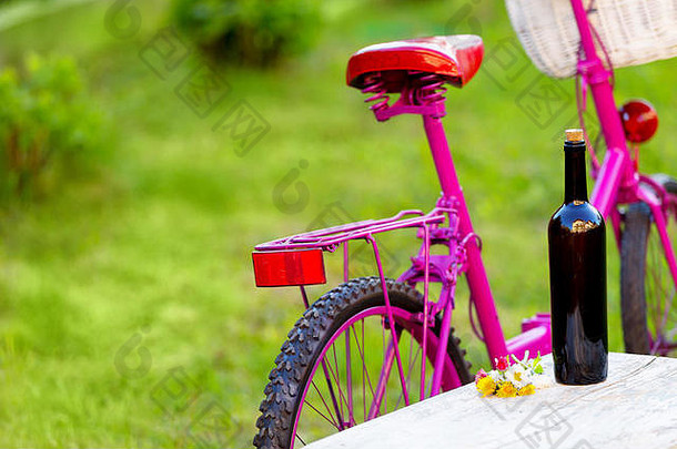 瓶红色的酒粉红色的自行车白色篮子野餐场景绿色草