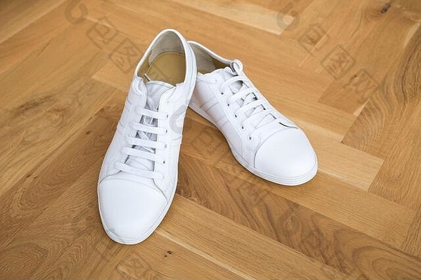 木质地板上的白色基本皮革时尚运动鞋