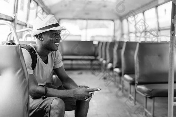 年轻快乐的非洲游客乘<strong>坐公交</strong>车时使用手机的剖面图