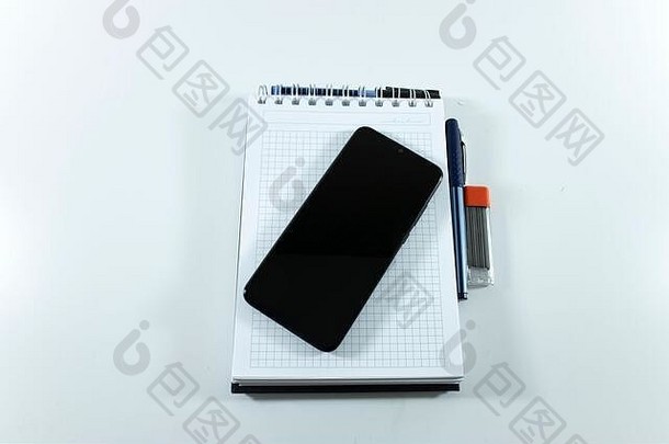 记事本手机笔的概念。这张照片是在白色背景和工作室拍摄的。闭合。
