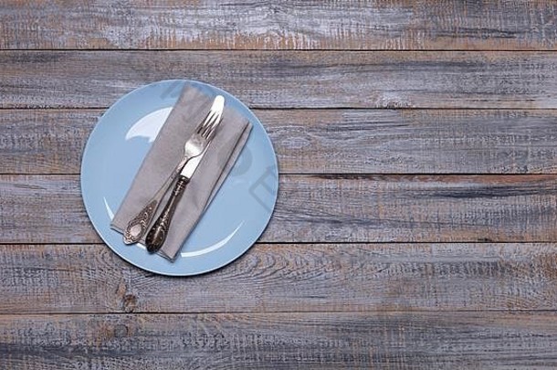 蓝色盘子、餐巾和<strong>餐具</strong>，背景是古老的灰色木质。从上面看。