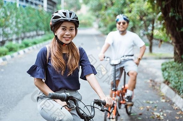 亚洲年轻的夫妻穿头盔享受骑自行车旅行公园