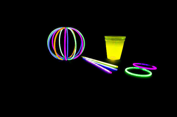 黄色荧光玻璃和带有荧光棒的球，背面背景为霓虹灯。不同颜色化学灯的变化