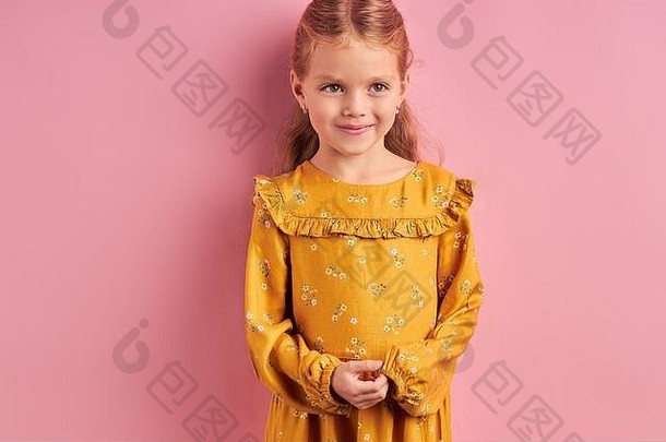 穿着黄色连衣裙的迷人女孩侧摆造型。粉色隔离背景