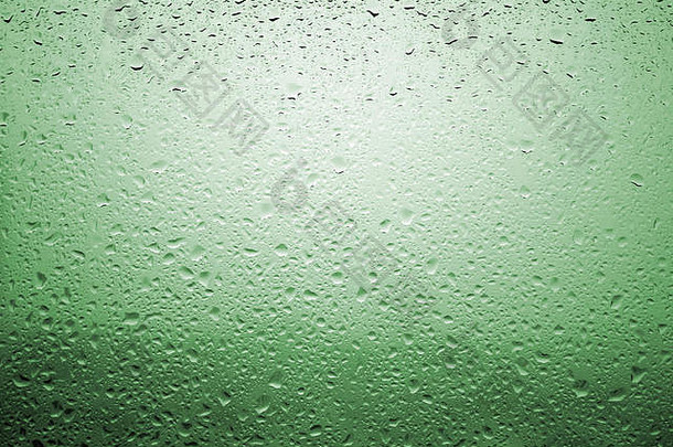 雨滴落在玻璃窗上，周围的景色非常分散，呈淡绿色