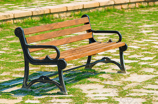 阳光明媚的日子里，公园里站着一张空木凳