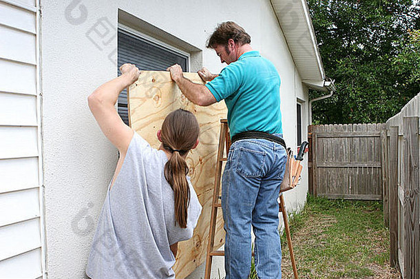 父亲儿子工作安装胶合板窗户准备飓风