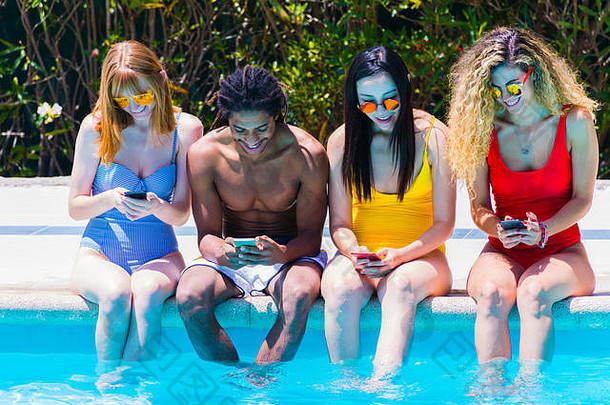 跨种族年轻的人坐着边缘池有趣的检查移动手机