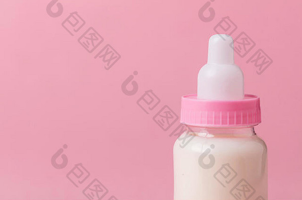 粉红色背景的装满牛奶的婴儿奶瓶