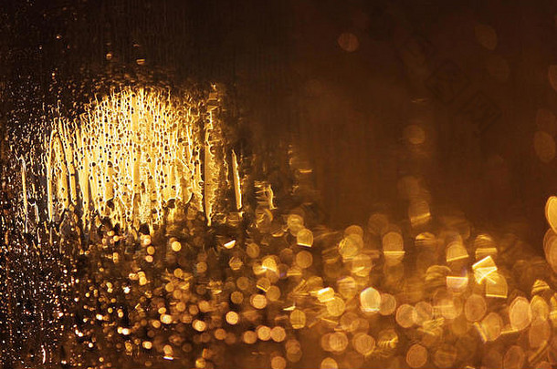 夜雨滴在金色的玻璃上，灯的光芒。博克。