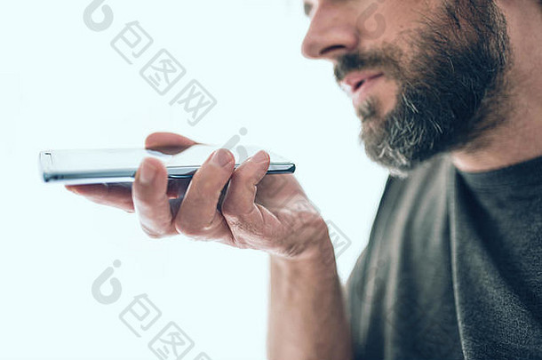 留胡子的白人男子在手机上录制语音信息或使用语音助手的特写镜头