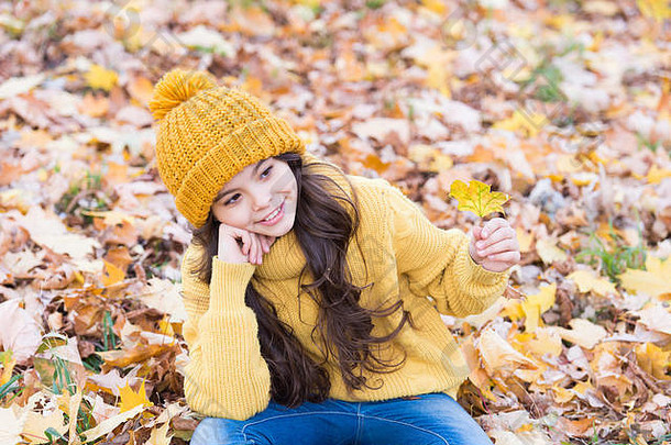 秋季护肤常规。孩子戴暖和的针织帽子。温暖的羊毛饰品。女孩放松秋天的自然背景。可爱的季节。保持今秋最温暖。孩子们在户外玩耍。无忧无虑，轻松自在。