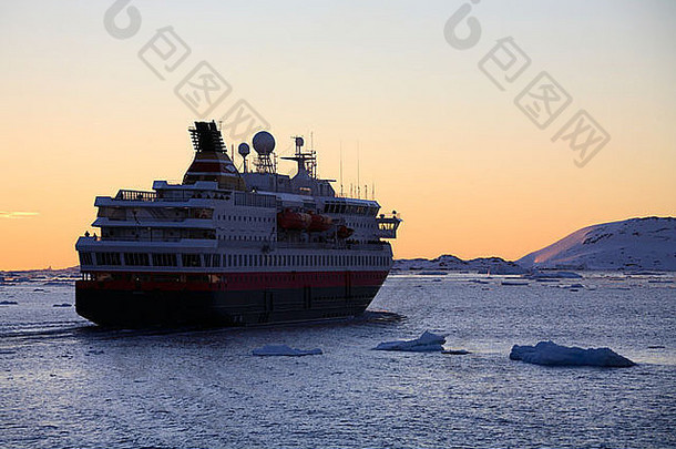 午夜的太阳和南极洲拉迈尔海峡的一艘大型旅游船。