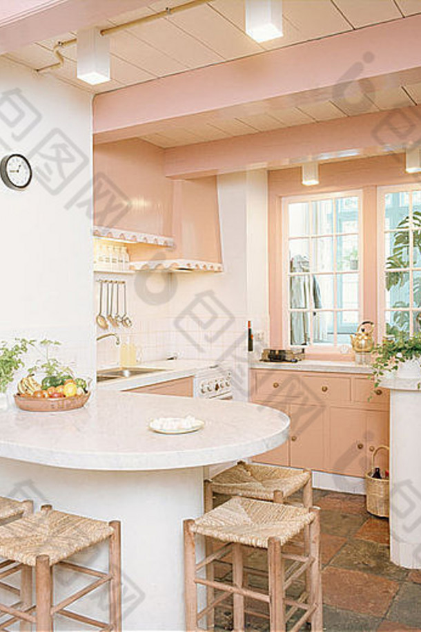 拉什坐在早餐吧的木凳子上，位于粉彩粉色的70年代厨房内，天花板为粉色横梁
