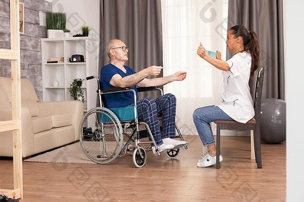 护士使用阻力带，并向老人解释如何使用阻力带。残障老人康复支持治疗理疗<strong>保健</strong>系统<strong>养老</strong>院社工