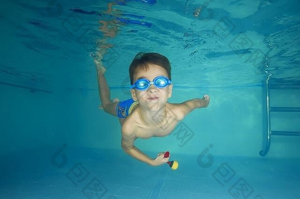 一个戴着护目镜的男孩在游泳池里玩水下游戏