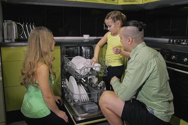妈妈。父亲教学女儿学习洗碗机情妇女孩孩子们加载把脏菜自动洗碗机