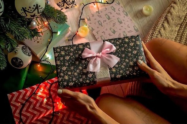 新年概念，一个女孩打开一个盒子，盒子里放着圣诞树附近<strong>的</strong>礼物，一个发光<strong>的</strong>花环，蜡烛和礼物。新年或圣诞节<strong>的</strong>顶视图