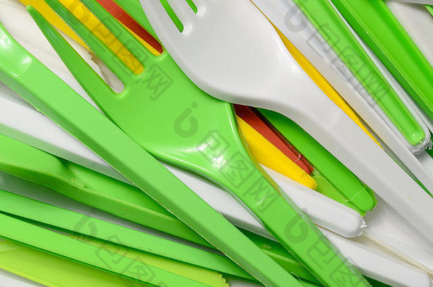一堆亮黄色、绿色和白色的二手塑料厨具。生态问题。塑料污染