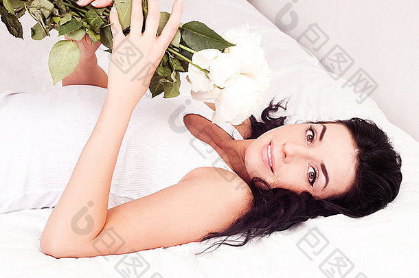 家里床上放着玫瑰花的美丽年轻女子