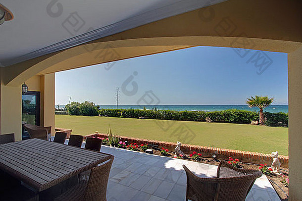 西班牙大别墅阳台上的木制餐桌和柳条椅可以看到大海
