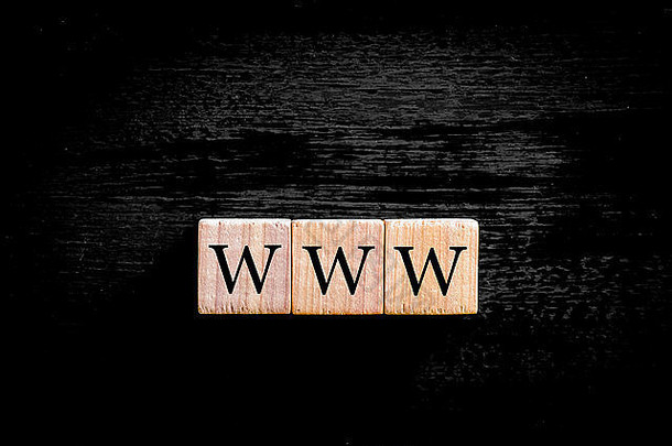 首字母缩写WWW-万维网。木质小立方体，黑色背景上有字母隔离，有复印空间。商业概念图。
