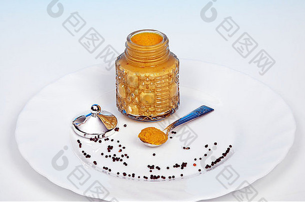 玻璃芥末罐中的英国芥末，前景是芥末籽。