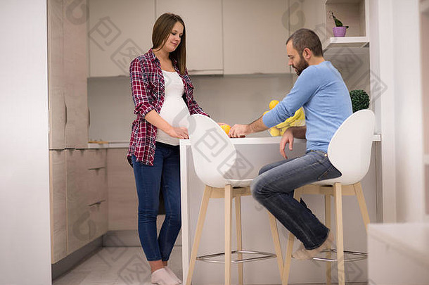 年轻的怀孕了夫妇烹饪食物水果柠檬汁厨房生活方式健康的怀孕快乐生活概念