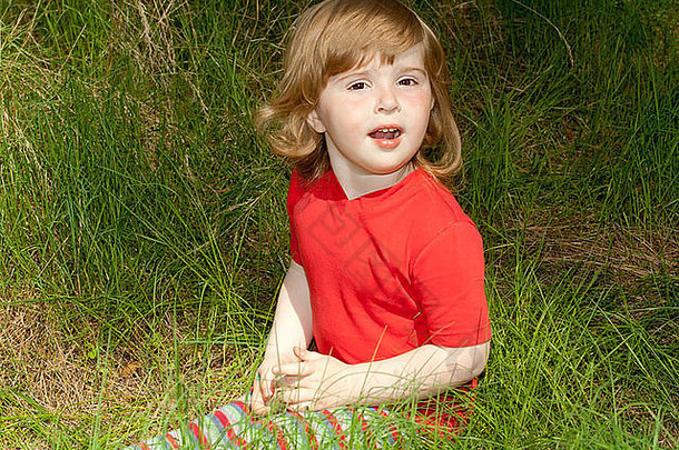 一个小女孩坐在草地上唱歌