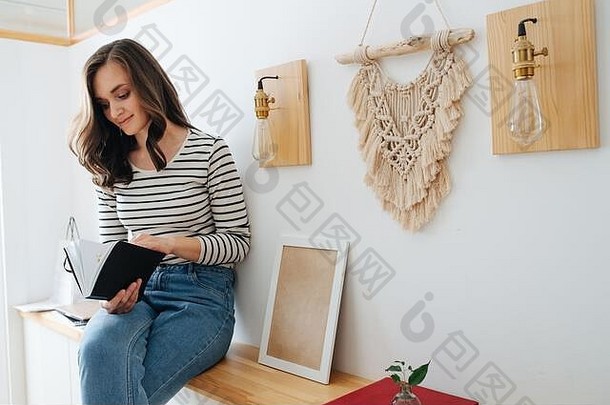 年轻的快乐浅黑肤色的女人女人坐着架子上阅读书