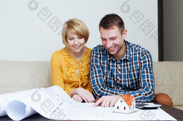 一对幸福的年轻夫妇坐在沙发上看着蓝图