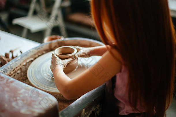 年轻陶工的双手，特写手在陶轮上制作杯子